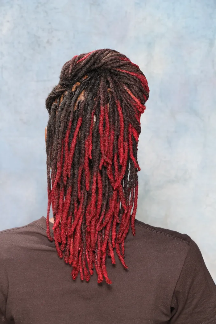 Red-tipped locs swept into a high ponytail, back view