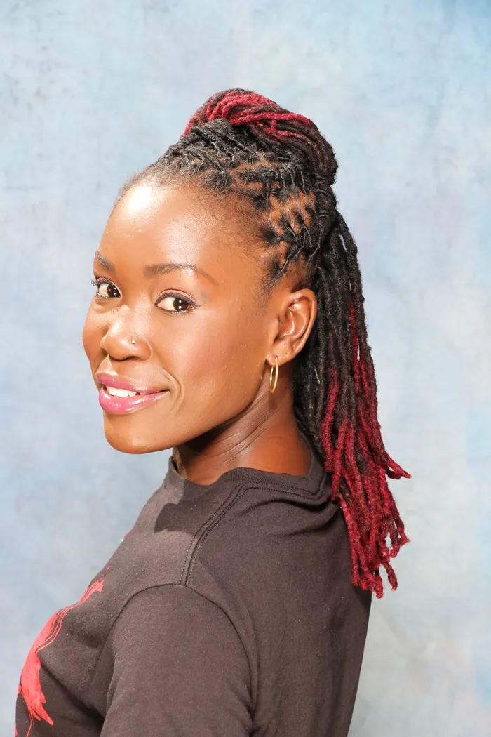 Client smiling with red-tipped locs in a high ponytail