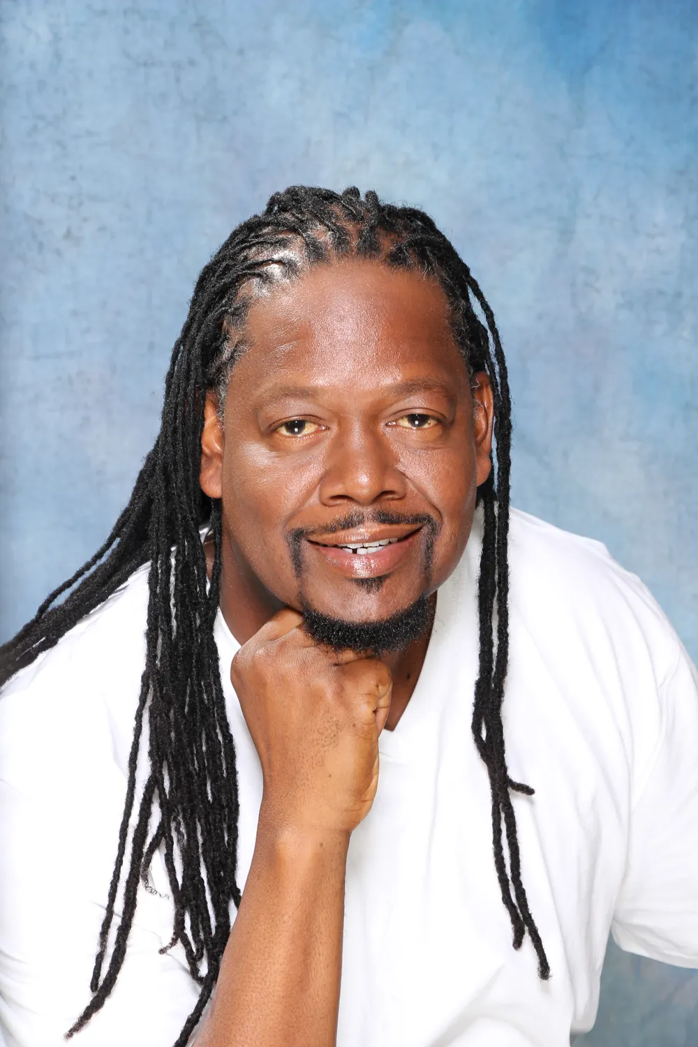 Front view of a client with long traditional locs, smiling
